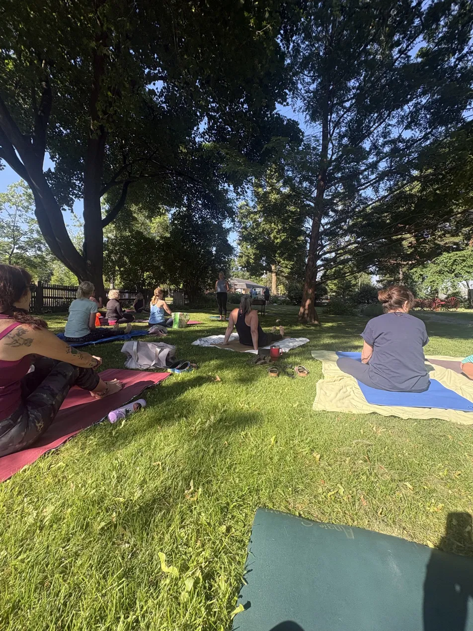 A circle of students listening to the instructor on a sunny lawn